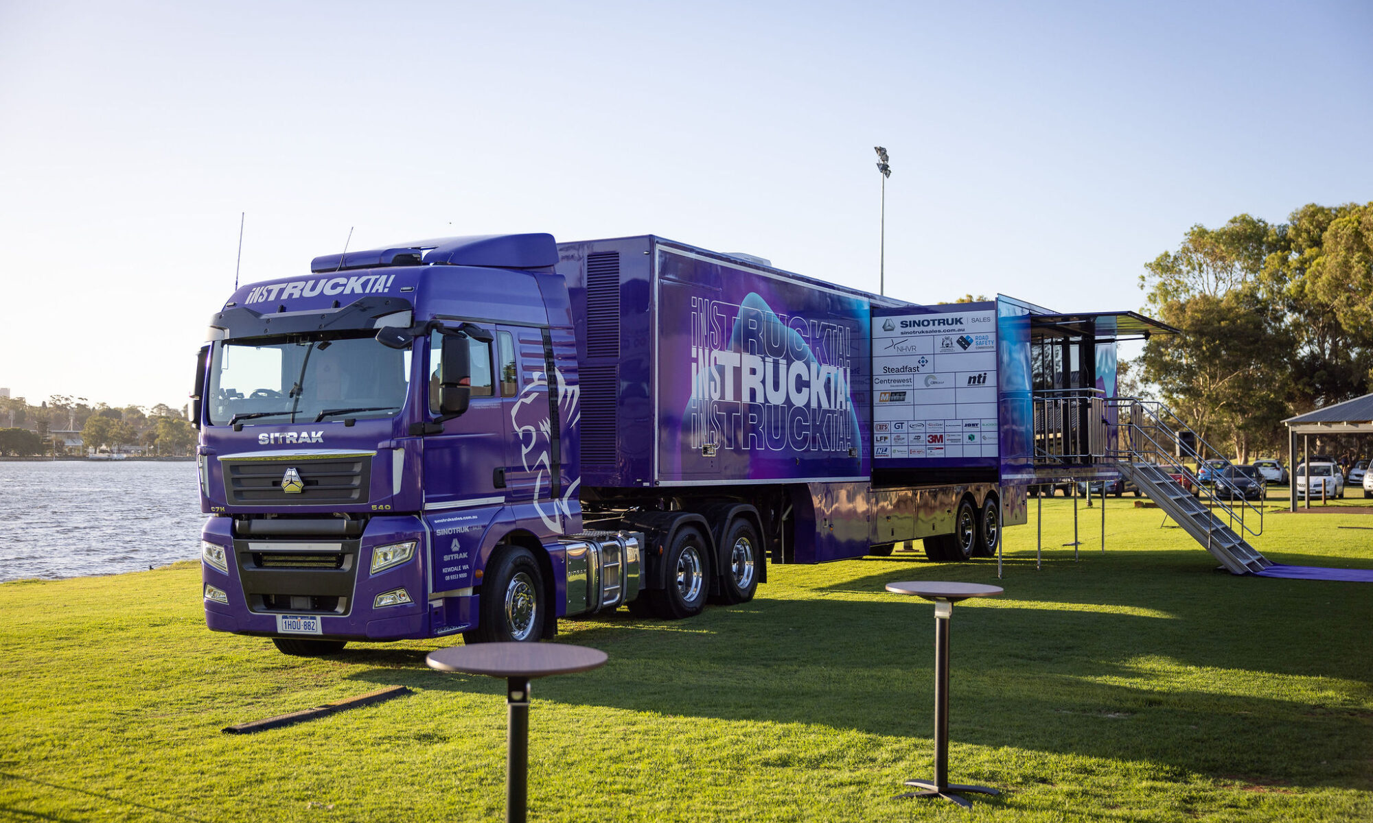 photo showing a large purple semi-trailer truck with iNSTRUCKTA branding. It has a slide-out section opened up on the trailer which folds down to steps so that visitor can access the displays inside.